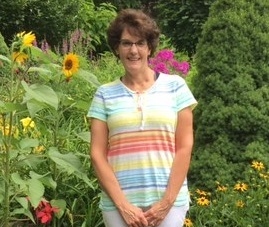 Stephanie standing in a garden with sunflowers in the background.