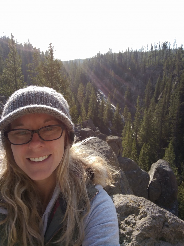 Half portrait of Kendra on a hike with mountains in the background